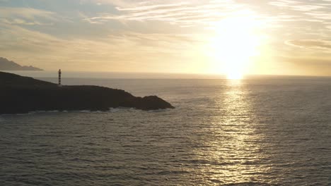 toma panorámica de un faro a la hora dorada con sol y océano