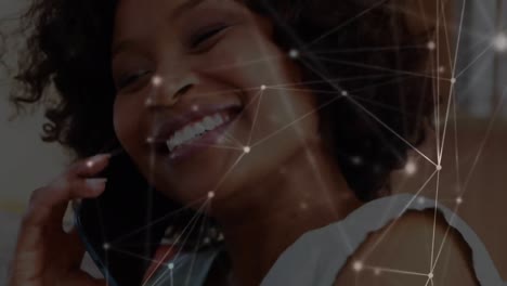 Animation-of-connected-dots-with-lines-over-smiling-african-american-woman-talking-on-cellphone