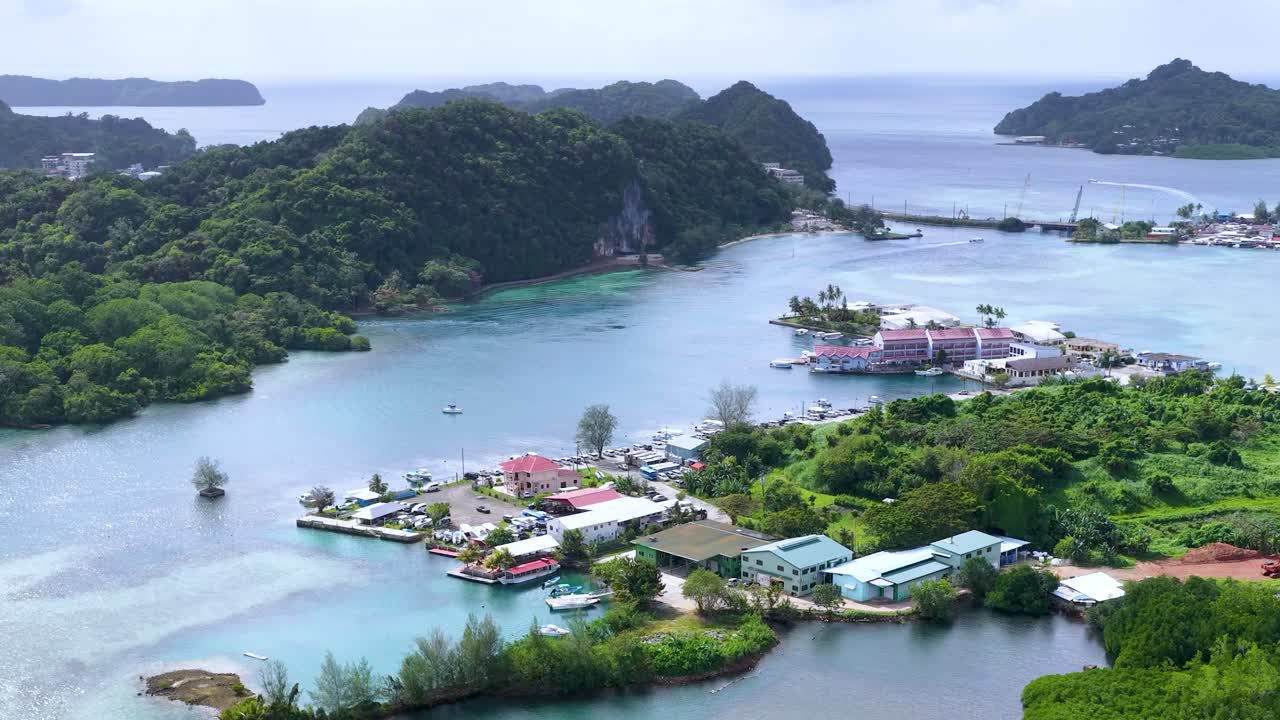 ภาพมุมสูงจากโดรนเหนือหมู่บ้านบนเกาะเขตร้อนที่มีน้ำทะเลสีฟ้าเทอร์ควอยซ์และพืชพรรณเขียวชอุ่ม