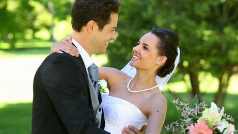 happy newlyweds dancing in the park