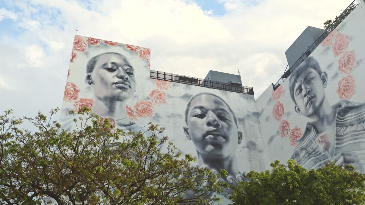 Close up shot of a mural at Wynwood Art District, Miami, depicting African and Latin children holding roses, with one extending hands in a prayer-like gesture.