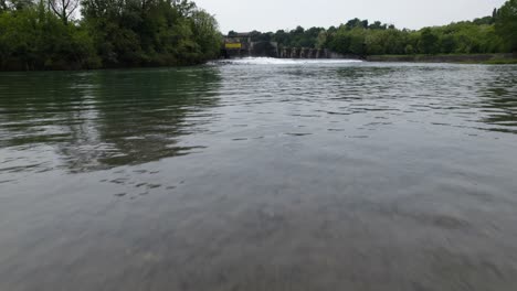 Drohnenschuss-Auf-Bodenhöhe,-Der-über-Das-Wasser-Eines-Sees-In-Richtung-Eines-Staudamms-In-Trezzo-Sul-Adda-In-Italien-Gleitet