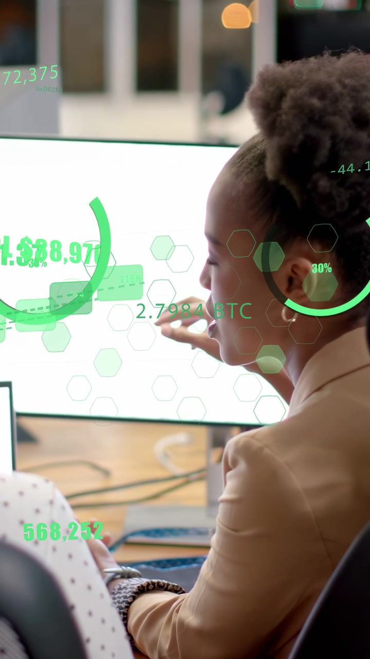 Vertical video: Woman turning to coworker pointing monitor causing green HUD explaining BTC values