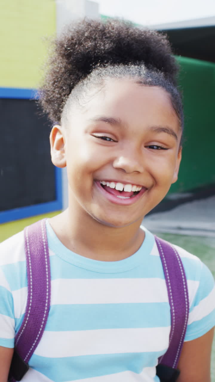 Vertical video of portrait of happy african american schoolgirl in school