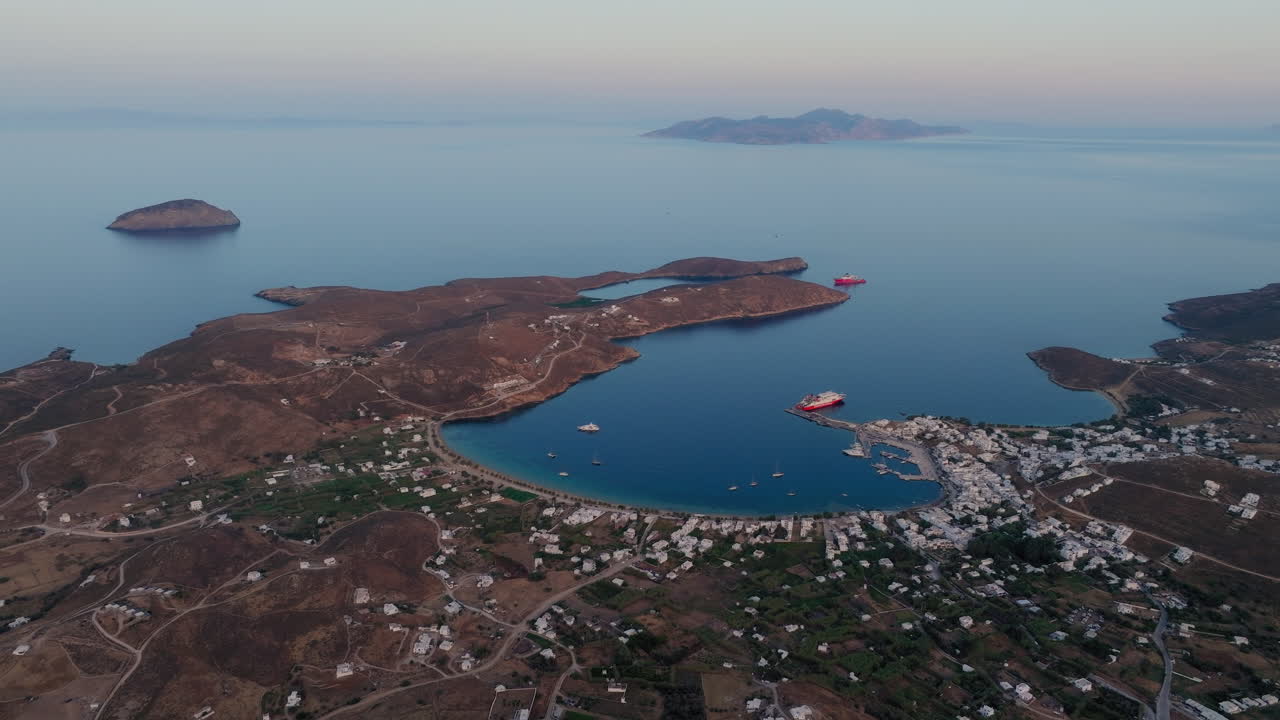 Slow panning drone shot of Livadi beach and main port of Serifos island during sunset