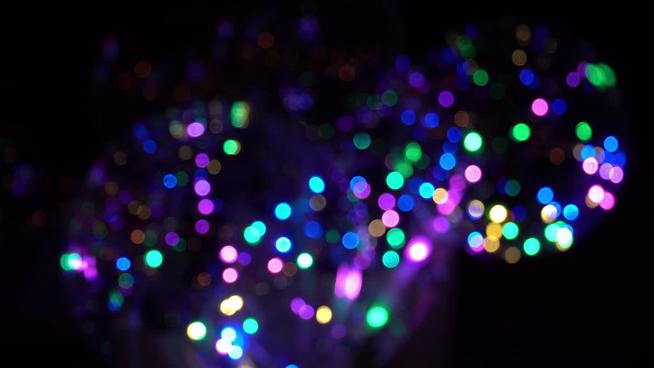 guirlandas coloridas piscando no escuro. fundo festivo abstrato com esferas multicoloridas colocadas em um avião e luzes de néon piscando aleatoriamente no escudo. lâmpadas de néon para shows ou eventos.