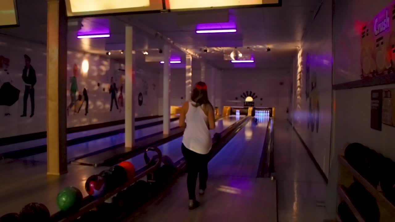 Bowling in una vecchia sala da bowling con una signora della lega notturna che lancia la palla.