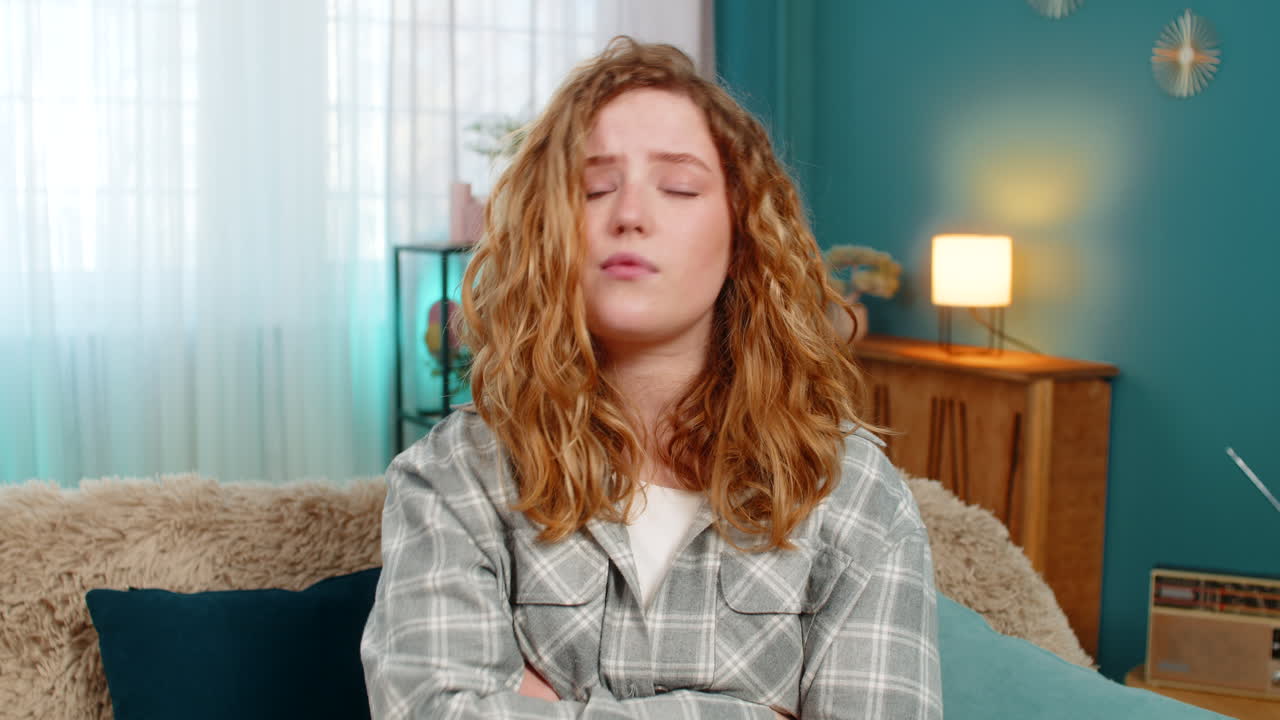 Woman sitting on sofa waving hand no with serious face expression showing disagreement and refusal