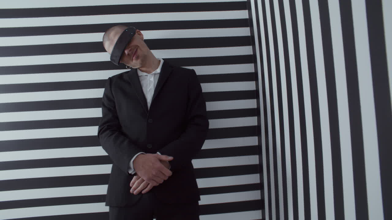 Man wearing VR headset and a black suit in a striped room