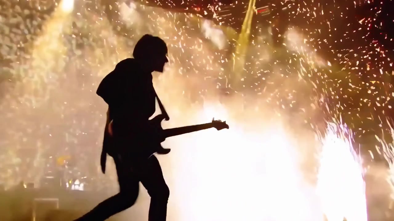 コンサートで特殊効果花火と紙吹雪の中、ステージで演奏するギタリスト。