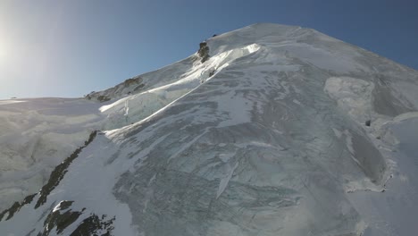 aerial, panoramic, icy mountain summit in the swiss alps with the sun behind