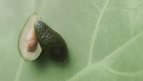 composition of halved avocado over green leaf background