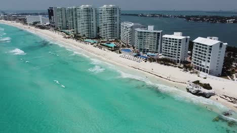 Cancun-beachfront-with-turquoise-waters-and-white-buildings,-bright-day,-aerial-view