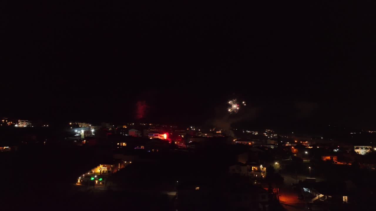 Aerial night view of a cityscape with glowing fireworks celebrating New Year's Eve