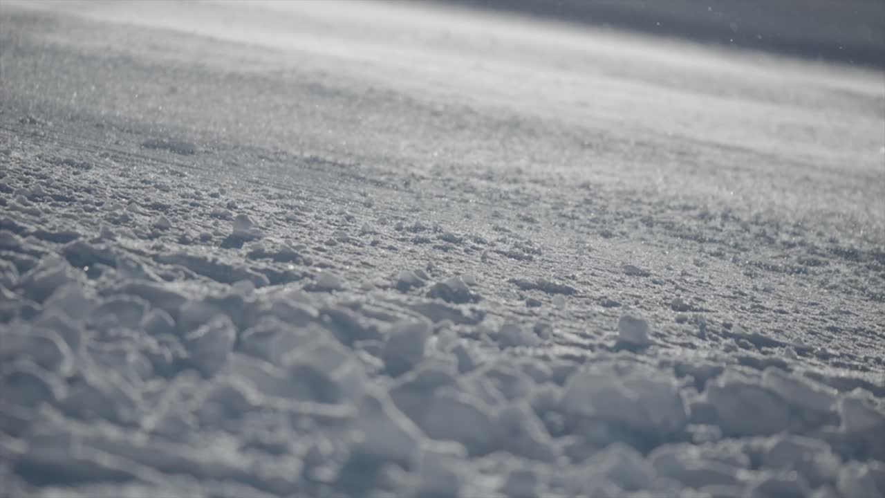 Ground Shot Of Snow Grains Flying Smoothly Over Snowy Surface