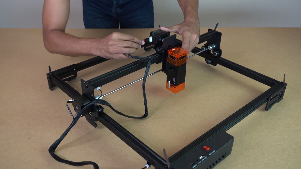 Man plugging cables into laser engraving machine, setup process