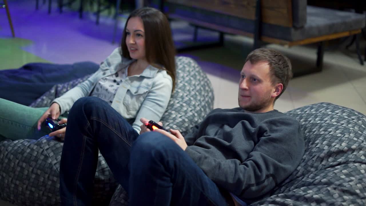 Young couple playing video game at home. Shooting and controlling using the game controller. Slow Motion shot