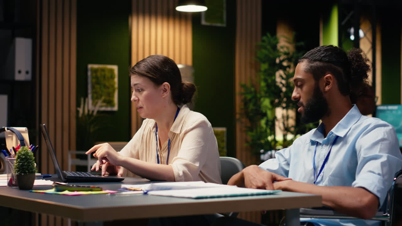 Office life with wheelchair user and woman collaborating at desk