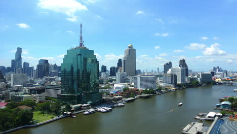 daytime timelapse of boats and ships moving along chao phraya river with high skyscrapers buildings like cat tower bangkok and lebua state tower on the river banks, cityscape panorama