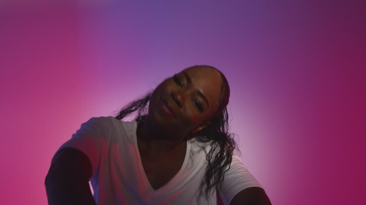 Studiebillede af ung kvindelig danser, der danser mod en blå og pink oplyst baggrund 13