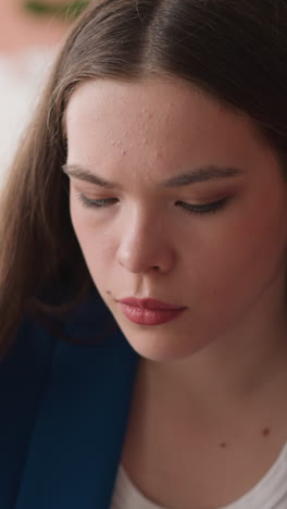 focused woman looks downward in library premise. young lady concentrates on reading sitting in university information center. reading woman closeup