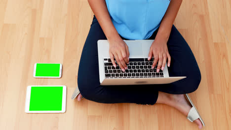 Female-executive-using-laptop-while-sitting-on-wooden-floor-4k