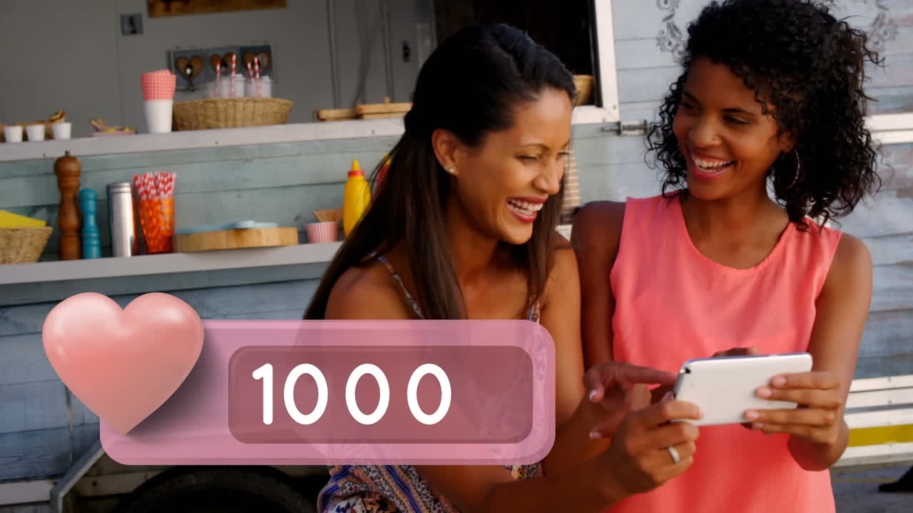 Black women laughing while looking at their phone