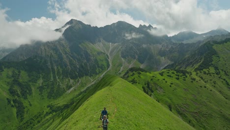 una pareja de caminatas a través de exuberantes colinas verdes con impresionantes vistas a las montañas en berwang, austria