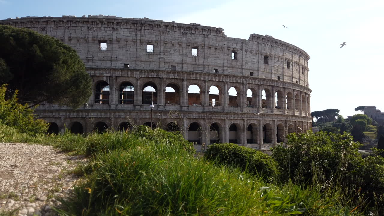 The colosseum from an higher side on a sunny spring day. Time-lapse,1o minutes long. Cars are passing by. People are walking on the sidewalk. motion lapse from left to right.