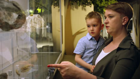 mother showing artifacts, animal bones to her son in a museum, close up shot