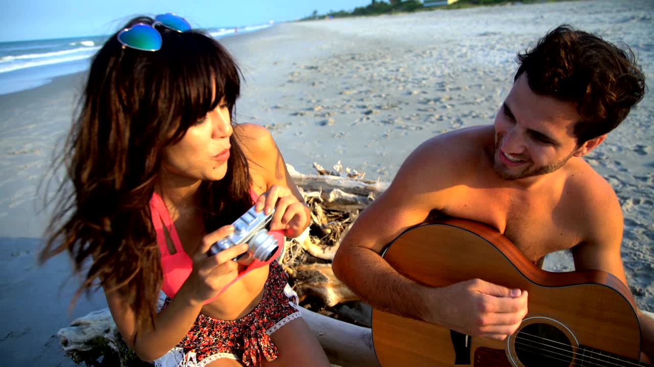 mujer hispana tomando fotos hombre caucásico tocando la guitarra