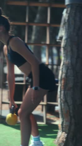 young woman doing kettlebell workout outdoors