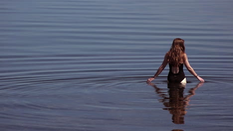 nordic woman bathing in glassy blue water with calm undulation in the limfjord, denmark