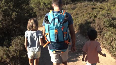 papá y dos niños caminando por el camino al aire libre