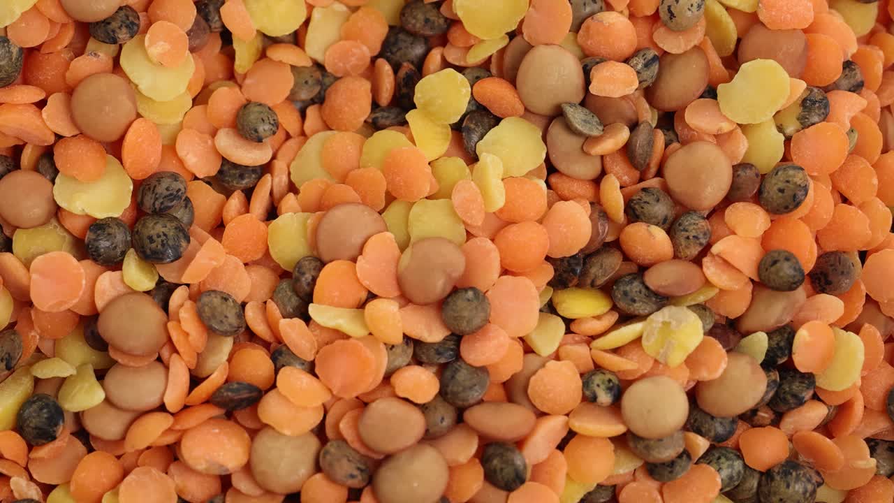 A spoon moves through a vibrant mix of lentils and seeds, highlighting texture and color in close-up detail