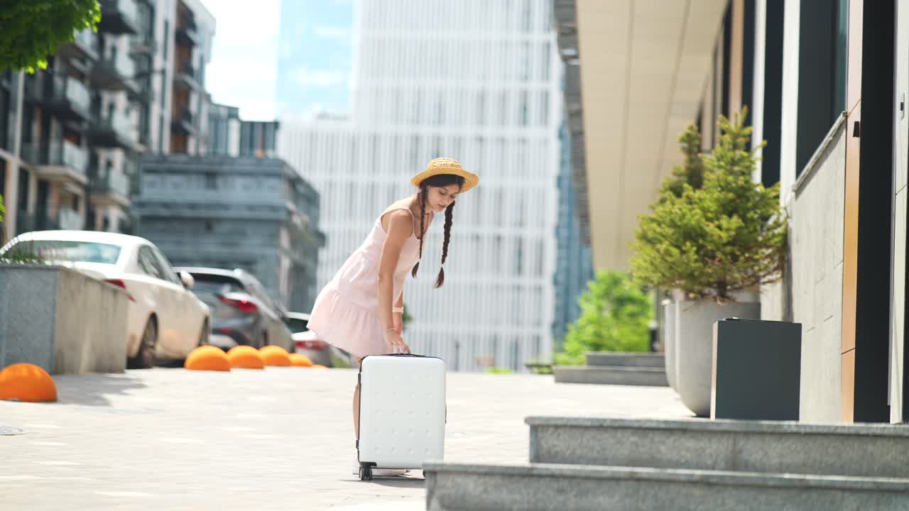 호텔 입구에 가방을 들고 있는 여자