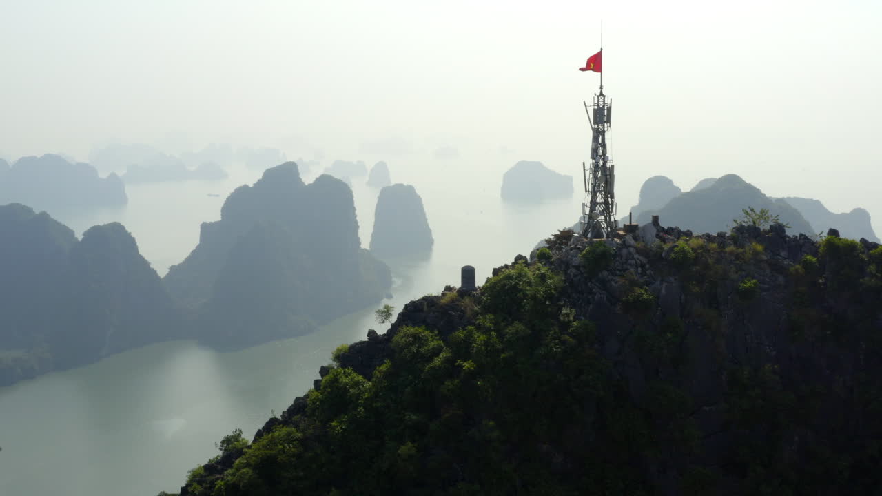 Aerial dolly approaching the communication tower on Bai Tho Mountain overlooking mist shrouded Halong Bay