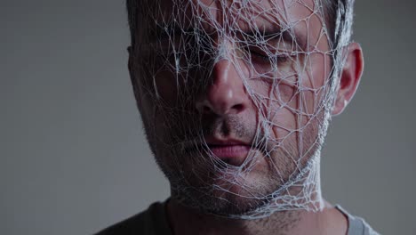 montage of a caucasian man with a net covering his face, conveying feelings of confinement, suffocation, and distress, against a neutral background