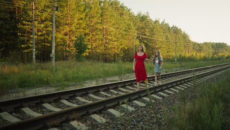 kid walking carefully on rail beam holding sister hand for support as they move together through rural countryside with sunlight casting soft glow on surrounding greenery