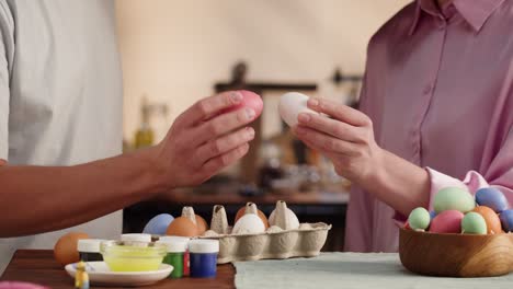 happy easter holiday. man and woman beating colored eggs close-up. people preparing for easter, painting and decorating eggs. christian celebration, family traditions.