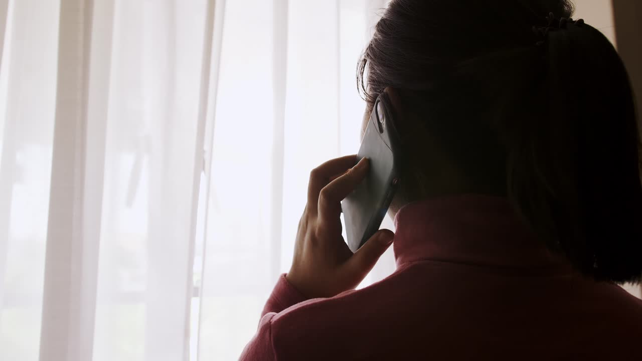 그녀의 휴대 전화에 응답하는 젊은 아시아 여자의 실루엣