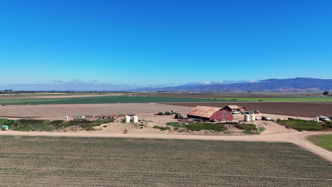 Red barn and farm equipment in wide Salinas Valley field, town of Chular, California, USA