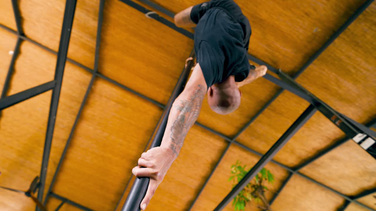 Uomo che esegue un esercizio acrobatico di pole dance a testa in giù