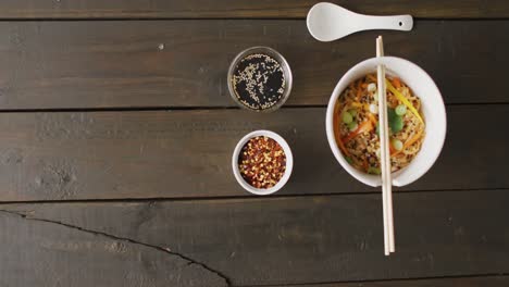 composition of bowl of pad thai with soy sauce and chopsticks on wooden background