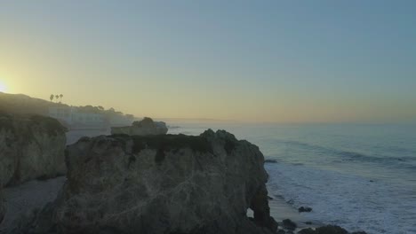 Aerial-shots-of-El-Matador-beach-over-breaking-waves-and-rocks-on-a-hazy-summer-morning-in-Malibu,-California