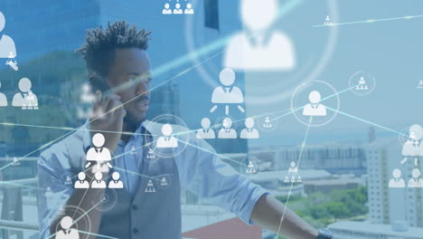 animation of connected icons over african american man talking on cellphone in balcony of office