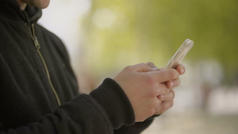 Captura-Recortada-De-Un-Hombre-Usando-Un-Teléfono-Celular-Al-Aire-Libre