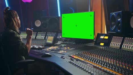 retrato de una elegante ingeniera de audio y productora que trabaja en un estudio de grabación de música, utiliza una pantalla verde de la computadora, una placa de mezcla, una mesa de control para crear una nueva canción.