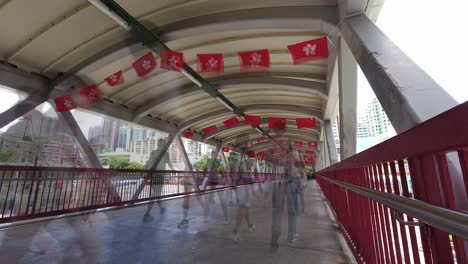 busy pedestrian bridge decorated with hong kong and china flags, time lapse