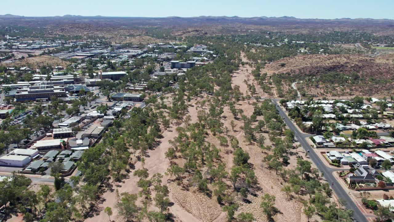 Aerial view of the dry Todd River in the full sun with the central business district of Alice Springs, Mparntwe, on the left. Northern Territory, Australia. August 2022.